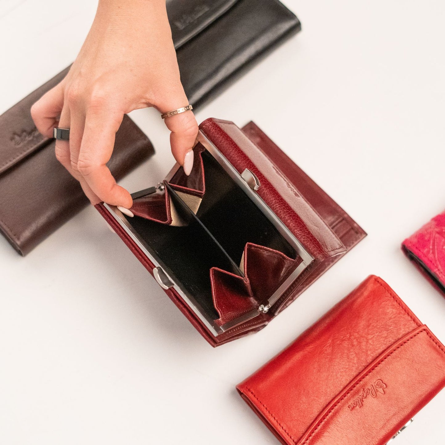 Papillon genuine leather ladies wallet in deep red held open showing compartments with other wallets nearby