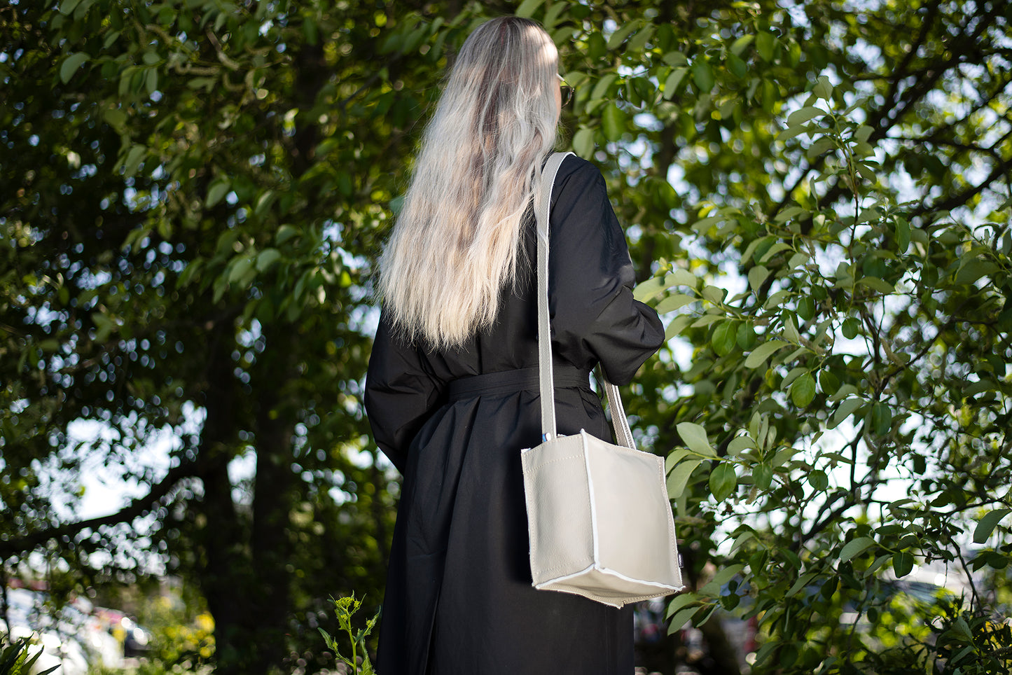 Trendbag light grey shoulder bag worn by woman in black outfit outdoors with green trees background