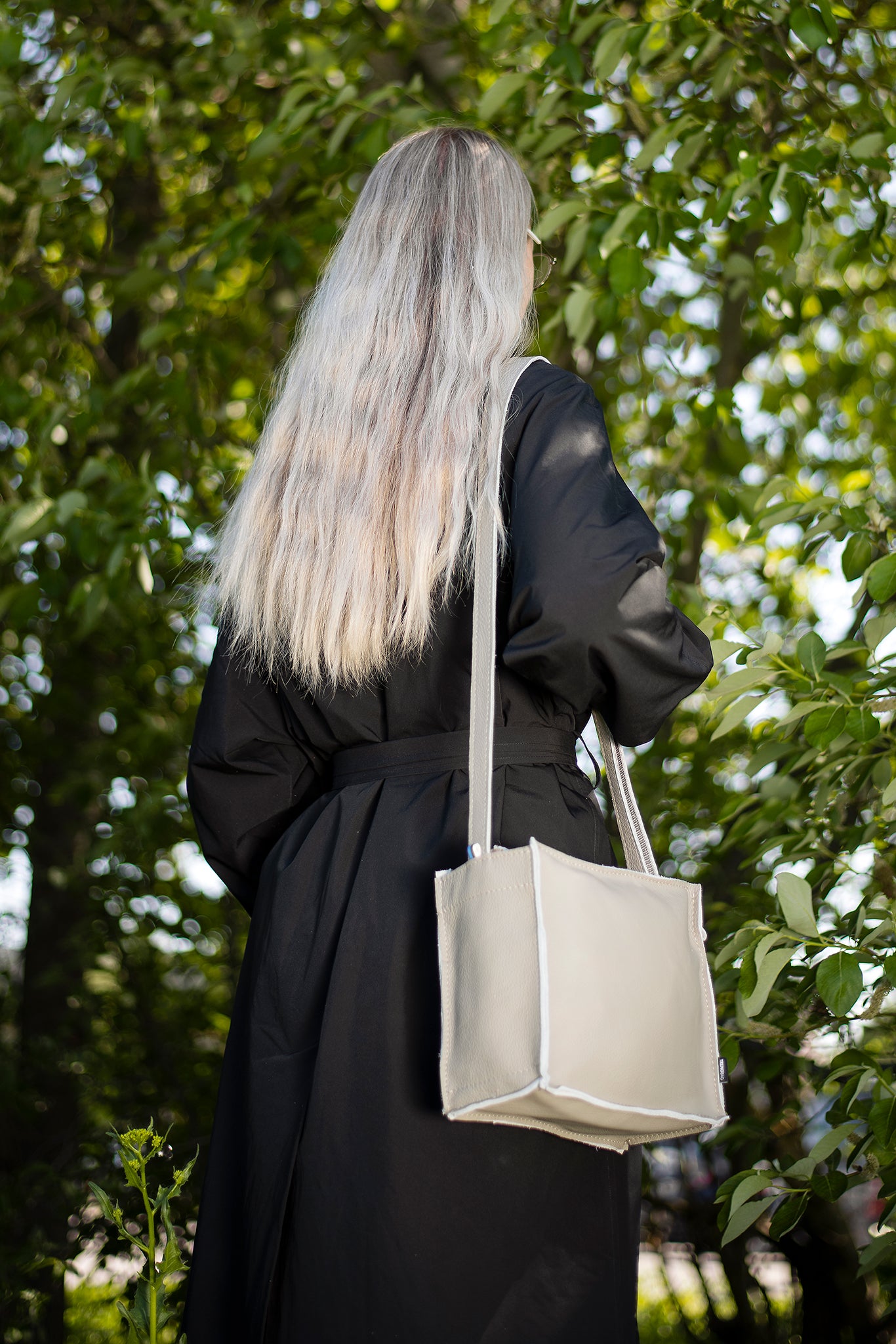 Light grey shoulder bag by Trendbag worn by woman with long blonde hair in outdoor setting
