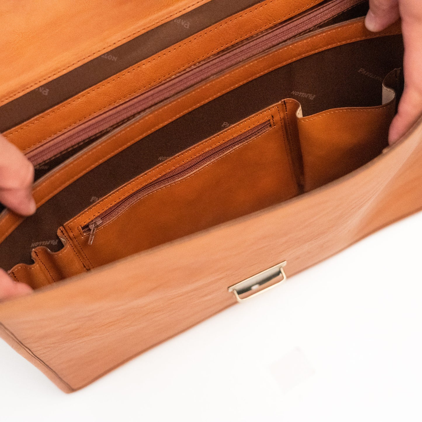 Open brown leather luxury office briefcase showing interior zippered and open pockets