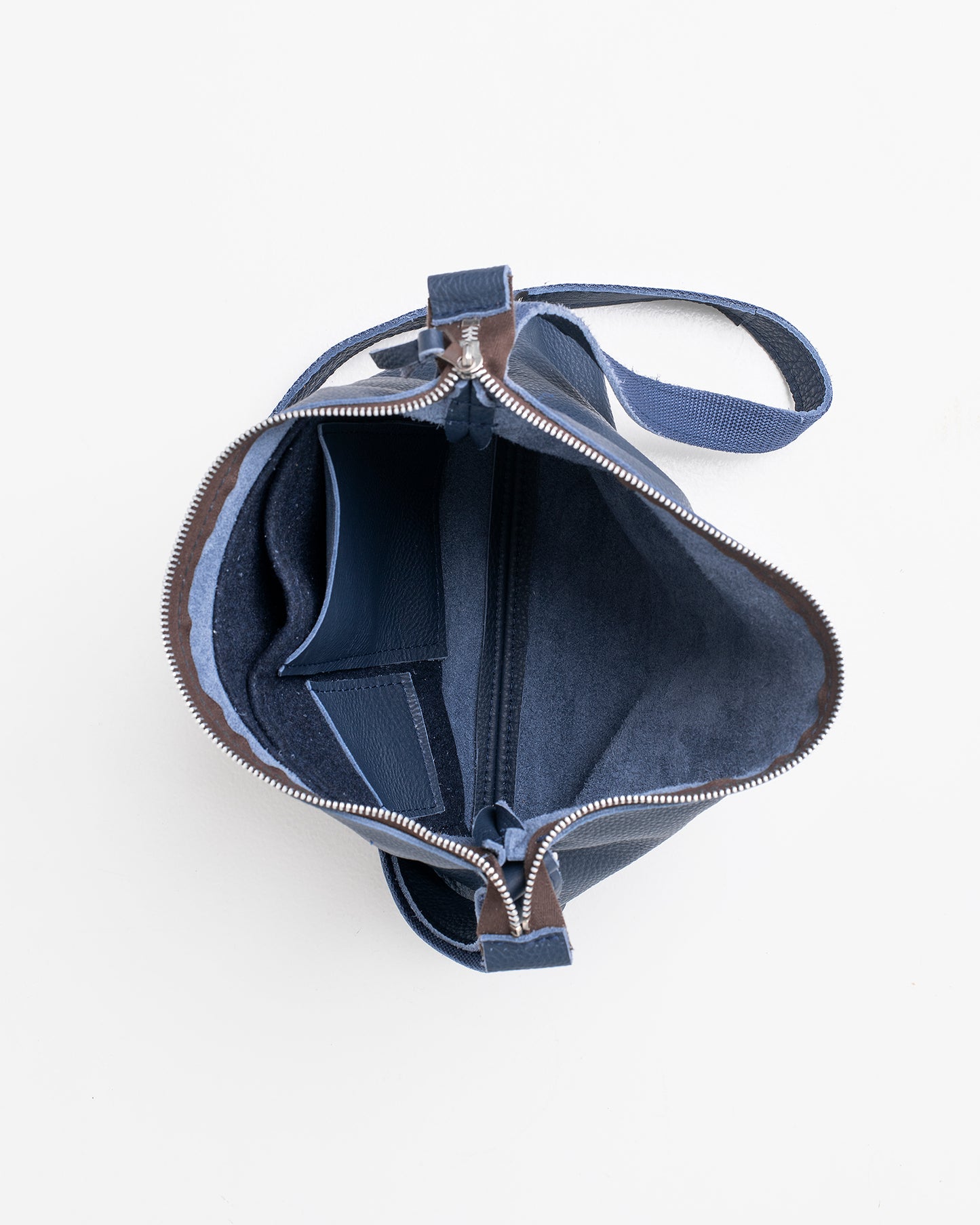 Top view of open dark blue leather shoulder bag showing interior compartments and zipper closure