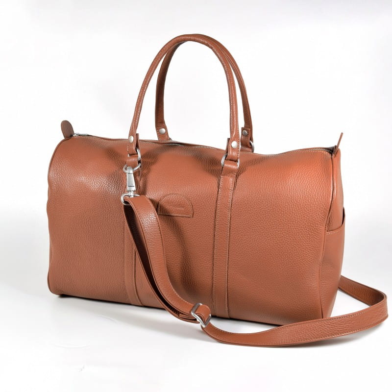 Handcrafted leather crossbody bag in brown with elegant stitching and minimalist design on wooden surface