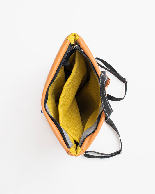 Top view of calvados brown leather backpack showing yellow interior and adjustable black straps