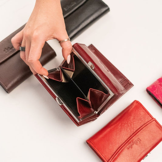 Papillon genuine leather ladies wallet in deep red held open showing compartments with other wallets nearby