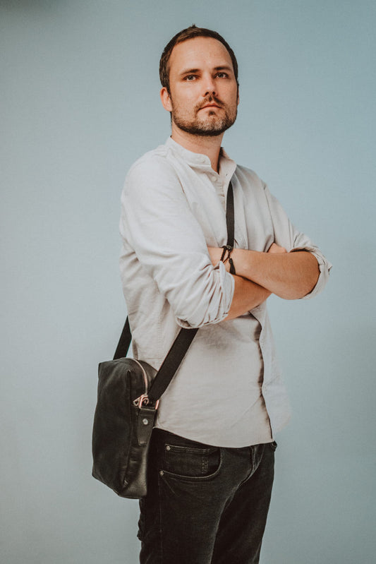 Man wearing Papillon small shoulder bag in black leather with adjustable strap