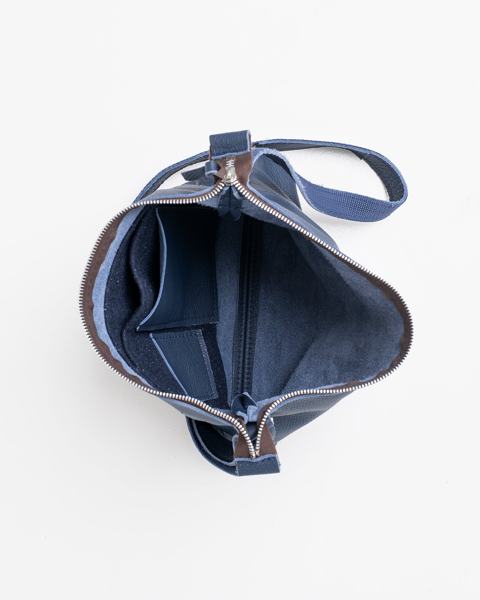 Top view of open dark blue leather shoulder bag showing interior compartments and zipper closure