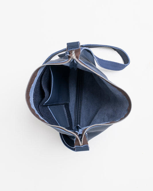 Top view of open dark blue leather shoulder bag showing interior compartments and zipper closure