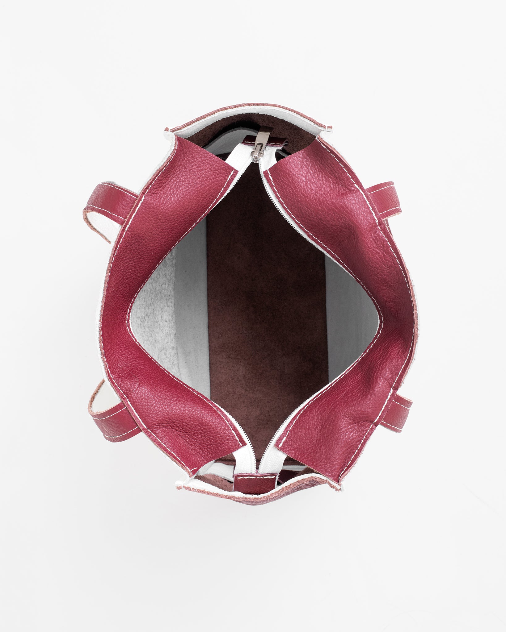 Top view of the inside of a white leather tote bag with maroon interior and handles by Trendbag